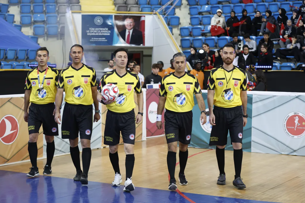 Match referees walking onto the court before an official Football Skating World Cup match