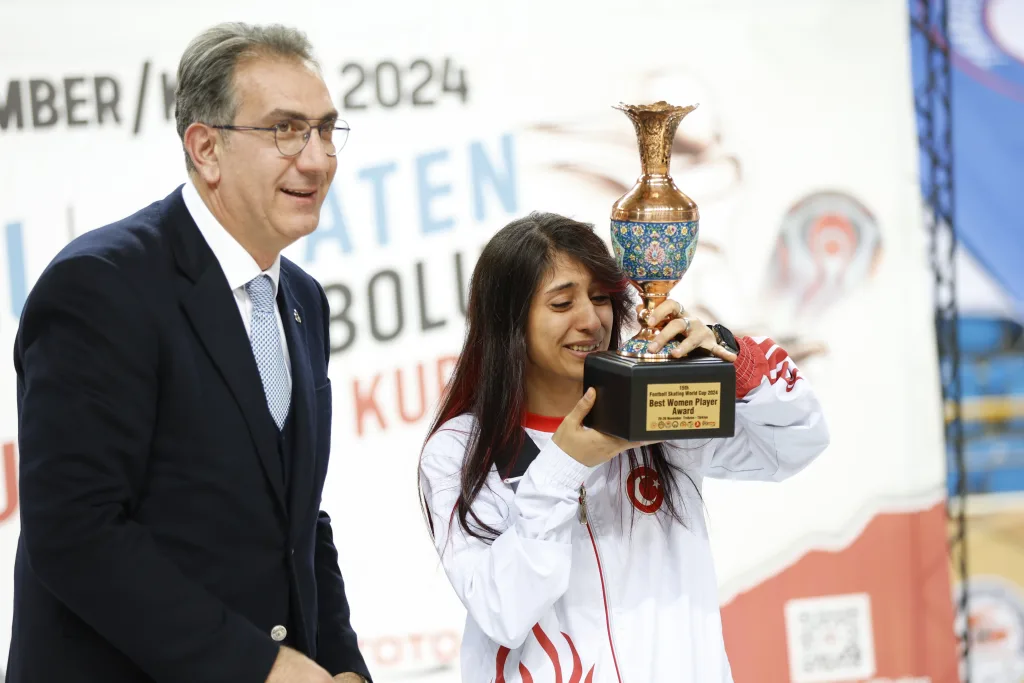 A woman athlete receiving a trophy at the award ceremony of the Football Skating World Cup 2024