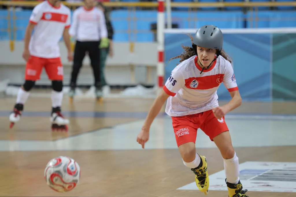 A young player controlling the ball on inline skates during an international junior match