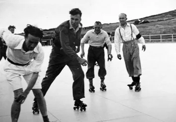 Archival black and white photograph of players contesting the ball on roller skates