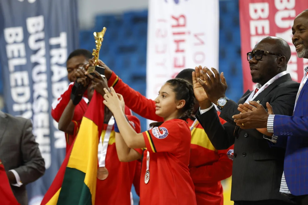 Junior athletes receiving their trophy from federation representatives at the closing ceremony